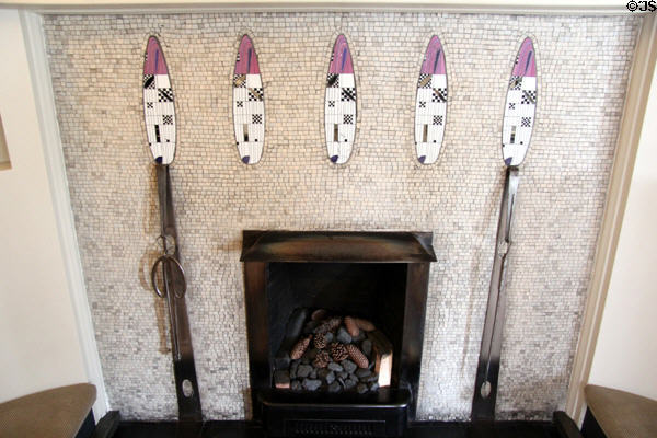 C.R. Mackintosh designed glass-mosaic petals inset into small tile surface of fireplace supporting architects steel fire-irons in drawing room at Hill House. Helensburgh, Scotland.