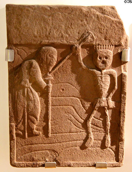 Stone tombstone (17thC) shows death as skeleton talking to old woman at Arbroath Abbey. Arbroath, Scotland.