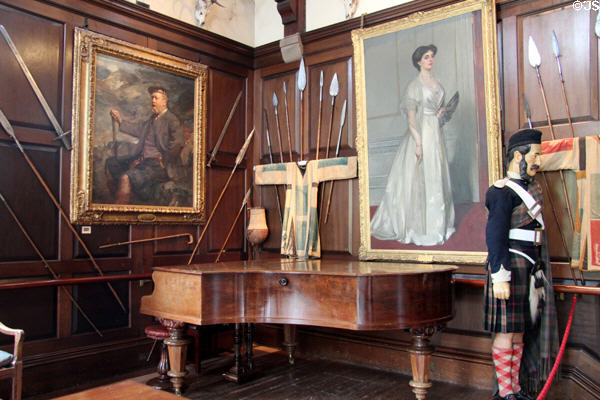 Clan portraits over grand piano surrounded by weapons in Ballroom at Blair Castle. Pitlochry, Scotland.