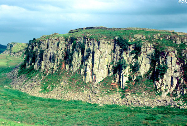 Hadrian's Wall dwarfed along top of rocky escarpment defended Roman Britannia from Pictish Scots. Scotland.