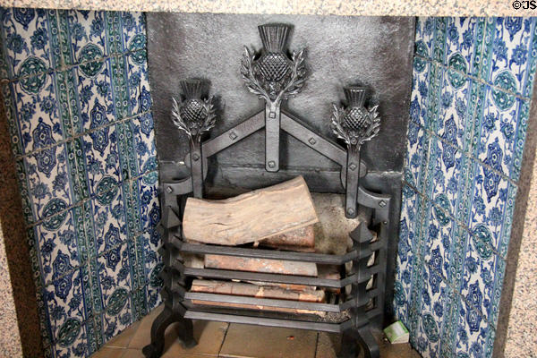 Wrought iron fireplace grate with thistles flanked by blue tiles at Drum Castle. Drumoak, Scotland.