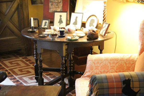 Drop-leaf table with tea service & silhouettes in yellow sitting room at Cawdor Castle. Cawdor, Scotland.