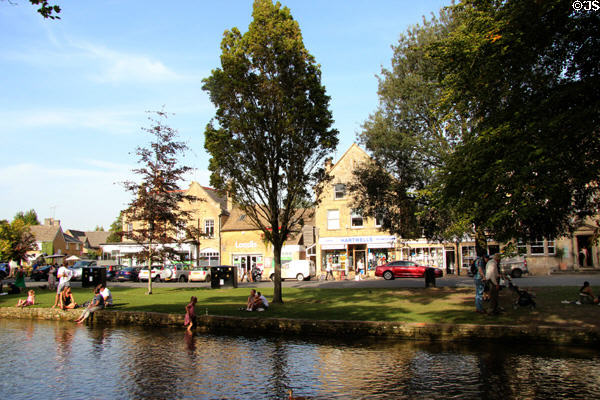 Holiday goers enjoying the River Windrush which runs through town. Bourton-on-the-Water, England.