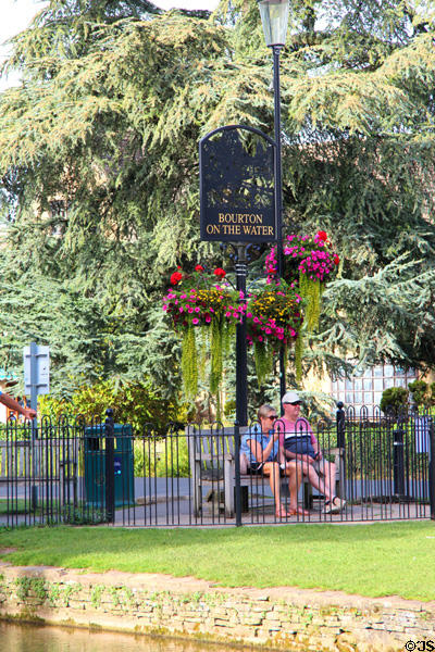 Bourton-on-the-water sign in town park on banks of river. Bourton-on-the-Water, England.