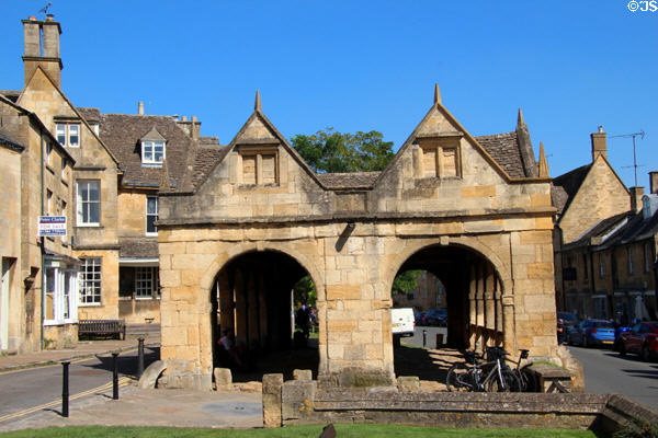 Vintage Cotswold stone buildings lining High St. with market hall in the center. Chipping Campden, England.