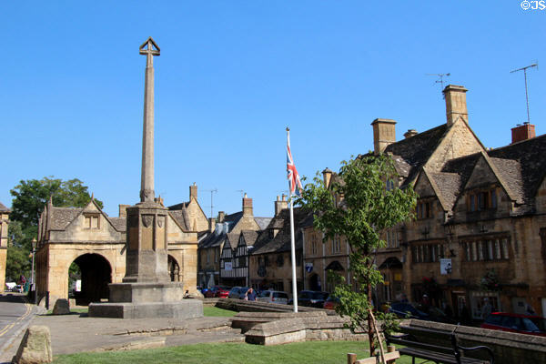 War memorial (1929) to men of town who died during WWI with market hall in background on High St. Chipping Campden, England.