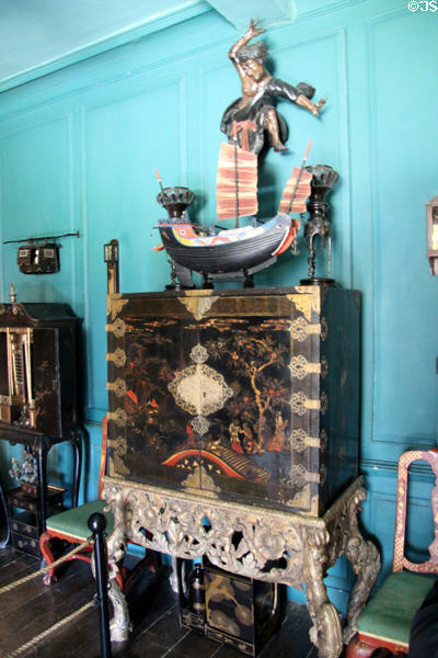 Oriental lacquered cupboard topped by model of junk at Snowshill Manor. England.