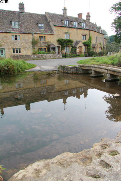 Homes reflected in still waters of River Eye. Lower Slaughter, England.
