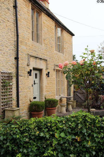 Cotswold stone home with roses & ivy in the front garden. Lower Slaughter, England.