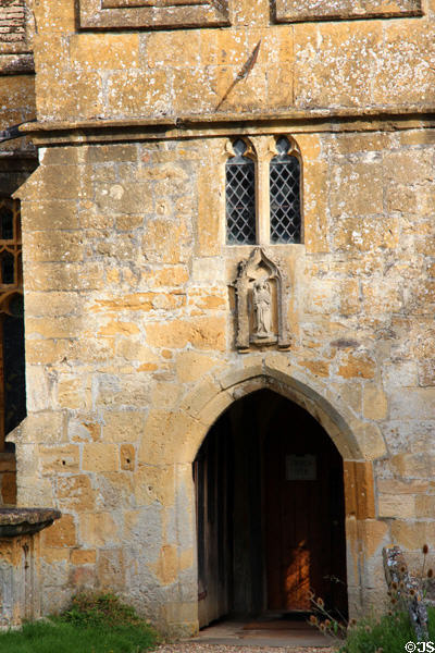 Entrance to St Michael Church with statue of saint above. Stanton, England.
