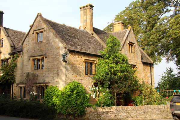 Steeply gabled Cotswold stone home with dry stone fence. Stanton, England.