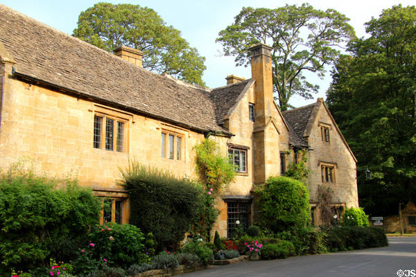 Large Cotswold stone residence lined by mixture of shrubs & flowers. Stanton, England.