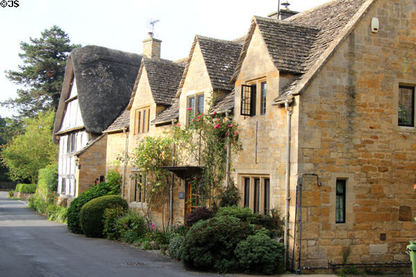 Row of typical Cotswold stone homes, including one with thatched roof. Stanton, England.