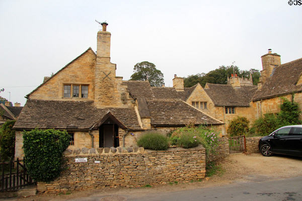 Typical Cotswold stone house with multi-sloped slate roof & elaborate chimney & fronted by dry stone wall. Upper Slaughter, England.