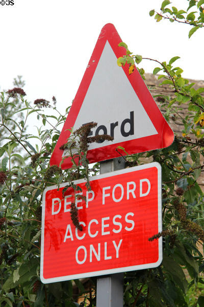 Warning sign indicating deep ford access across River Eye. Upper Slaughter, England.