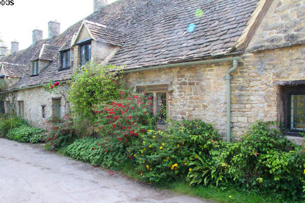 Row of Cotswold stone homes with dormers & slate roofs. Bibury, England.