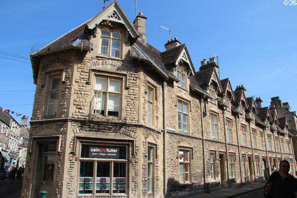 Row of vintage terraced cottages topped by dormer windows in shopping district. Cirencester, England.