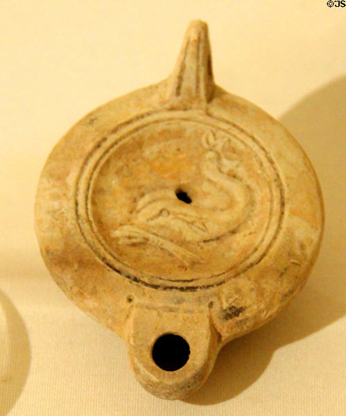 Roman era pottery oil lamp with lid decorated with dolphin which was considered a sacred animal at Corinium Museum. Cirencester, England.