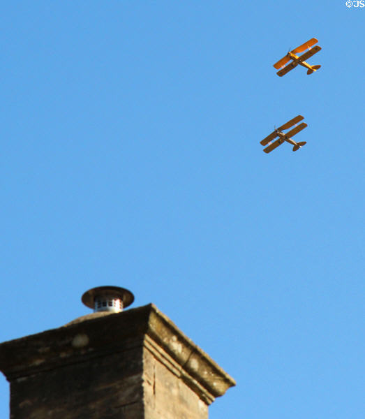 Vintage bi-planes from local air show flying over town. Northleach, England.