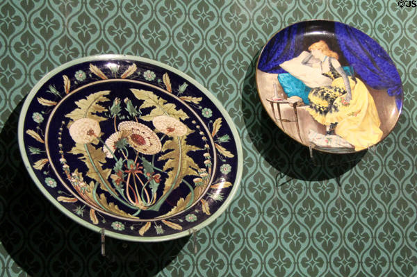 Earthenware plaque painted with dandelion (c1872) & plaque painted with fashionable woman 1879 by Herbert Wilson Foster both made by Minton of Stoke-upon-Trent at Potteries Museum & Art Gallery. Hanley, Stoke-on-Trent, England.