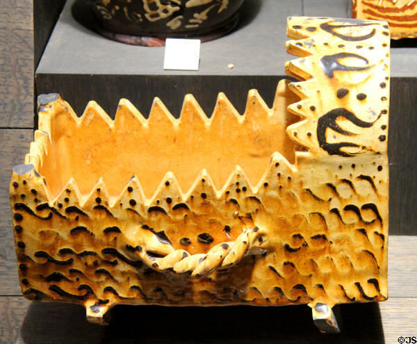Earthenware cradle decorated with red slip flowers (1839) by Fred Wootton of Little London, South Staffordshire at Potteries Museum & Art Gallery. Hanley, Stoke-on-Trent, England.