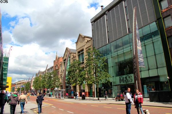 Streetscape of Donegall Place with curved pillars bearing names of ships built in Belfast. Belfast, Northern Ireland.