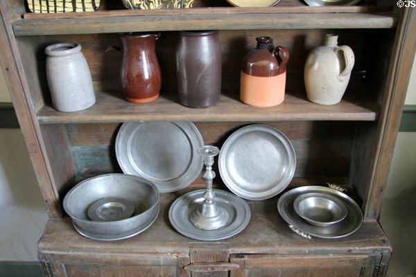 Cabinet with stoneware & pewter in brick house at Ulster American Folk Park. Omagh, Northern Ireland.