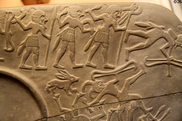 Details of Egyptian predynastic mudstone carved palette for grinding eye paint with hunters' scene (3250-3100 BCE - Naqada III) at British Museum. London, United Kingdom.