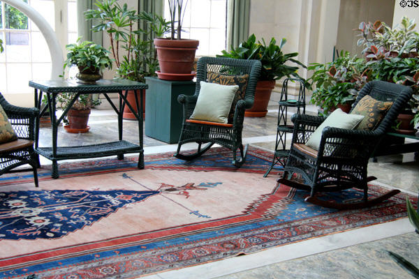 Wicker rocking chairs & table with potted plants commonly used in the early 20th C in conservatory at Eastman House. Rochester, NY.