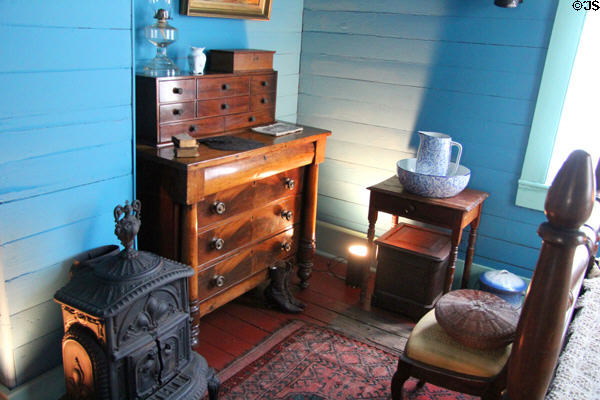Bedroom with desk & cast iron stove in Yates House at Sam Houston Park. Houston, TX.
