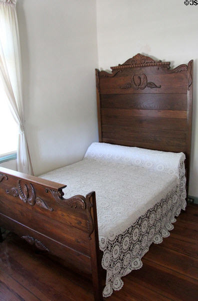 Finely carved wooden bed & crochet coverlet in Jahn House at Conservation Plaza. New Braunfels, TX.