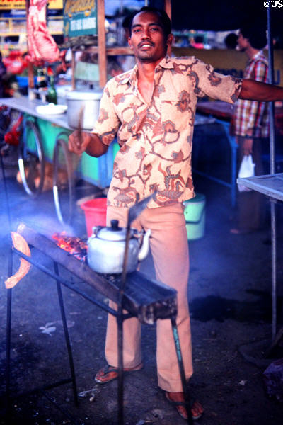 Street vendor grills skewers at Denpasar night market. Bali, Indonesia.