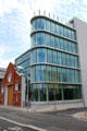 Glass facade of Campshire Hall wraps around preserved facade of old quayside warehouse on Sir John Rogerson's Quay. Dublin, Ireland.