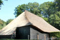 Simple building whose thatched roof structure, technically called eves, extends significantly beyond exterior wall, likely employed to help protect building from rainfall, at Arnhem Openlucht Museum. Arnhem, Netherlands.