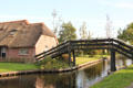 Pedestrian arched wooden bridge over canal. Giethoorn, Netherlands.