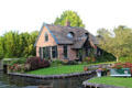 Home with ornate thatched roof broken with pair of windows on intersection of main & side canal. Giethoorn, Netherlands.
