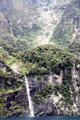 Rocky cliff and waterfall plunges into Milford Sound. New Zealand.