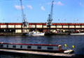 Antique cranes in front of former warehouses at Bristol's Floating Harbour, a tidal by-pass of the Avon River which kept ships from being stranded during low tide after docking at Bristol. Bristol, England.