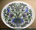 Underglaze-painted plate with bold floral design on bright white background made by Bristol Pottery at Bristol Museum & Art Gallery. Bristol, England.