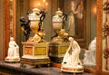 French mantle clock with Eros & snake handles around horizontal number rings by Jean-Baptiste Lepaute & Pierre Henry flanked by porcelain figures of war & peace by Dihl & Guérhard of Paris at Metropolitan Museum of Art. New York, NY.