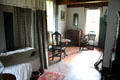 Canopy bed, table, chairs, chest & spinning wheel in Schenck House bedroom at Old Bethpage Village. Old Bethpage, NY.